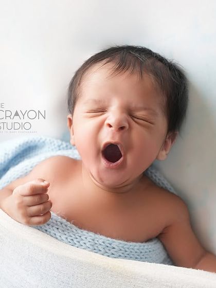 The biggest, most satisfying yawn from a tiny baby, captured while nestled in a soft hammock. A simple, authentic moment of newborn life.