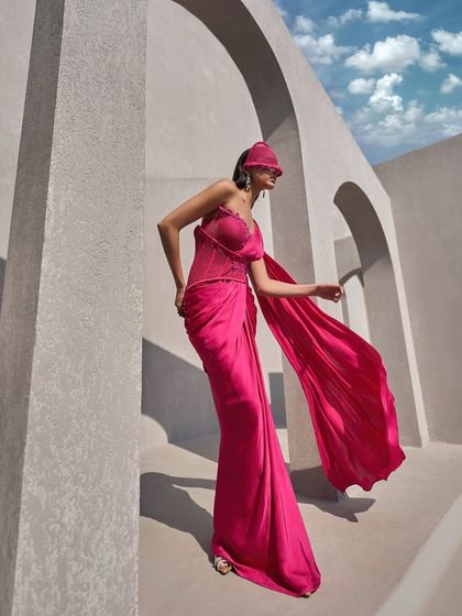 This hot pink corset sari is draped with boldness. The fluid movement of the pallu and skirt contrasts with the structured, cinched bodice for a revolutionary take on the sari.