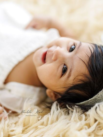 Another precious shot from this session, showing the baby's calm and content gaze. The soft lighting and textures create a dreamy and gentle portrait.
