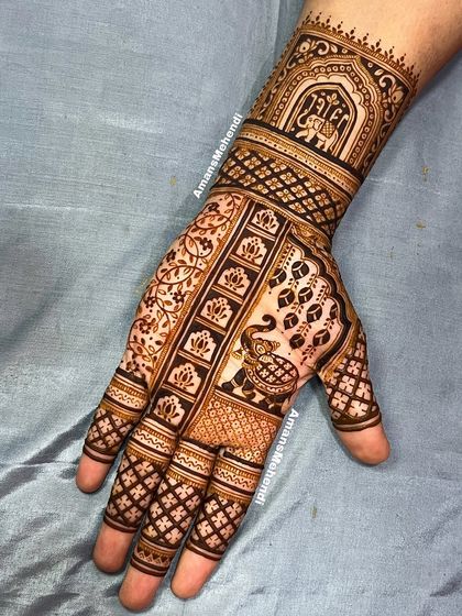 This design features a peacock on the palm and an elephant in a jharokha on the wrist. The use of geometric and floral patterns creates a rich and dense look.