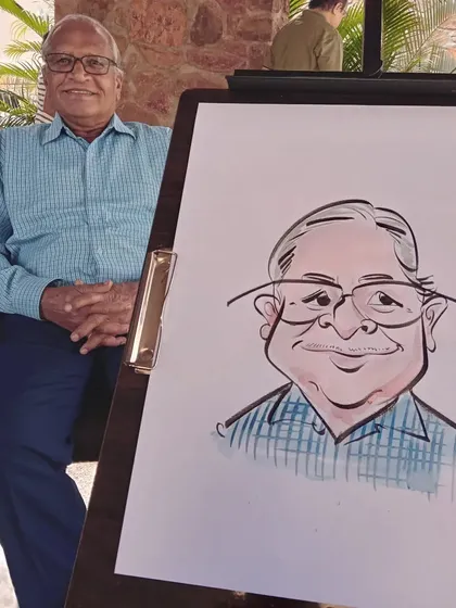 A gentleman sits beside his finished portrait, which accurately captures his likeness in a fun, artistic way.