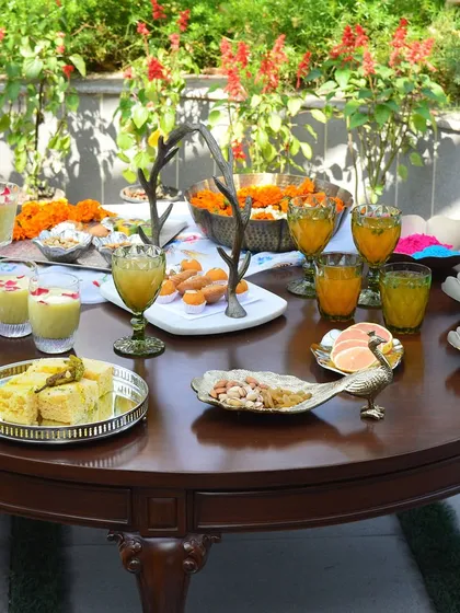 A full table spread for a Holi party. My serveware is used to present thandai, gujiyas, and other festive treats, while bowls of gulaal add to the colorful and joyous atmosphere.