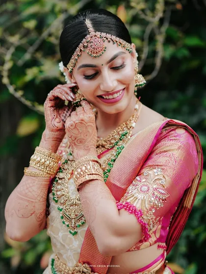 A beautiful bridal portrait showing the final touches being made to her earrings, a moment of quiet preparation.