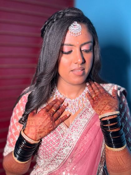 A candid moment with Vaani, showing off her soft pink eyeshadow and elegant diamond jewelry. Her henna-adorned hands complete this beautiful reception style.