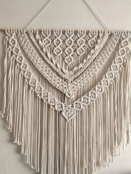 A classic layered macrame wall hanging with multiple tiers of detailed patterns. This timeless design is versatile and works well in a bedroom, living room, or entryway.