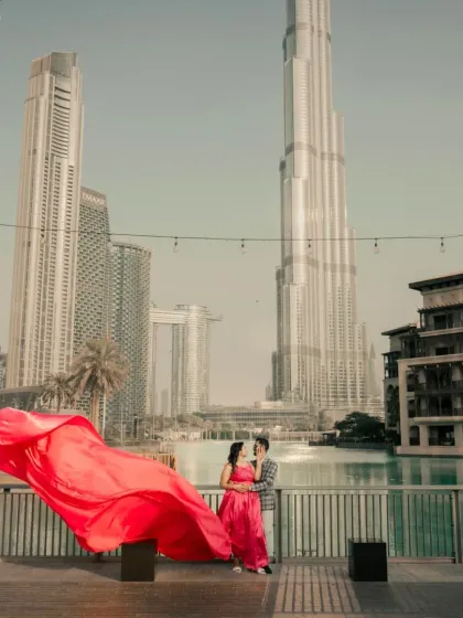 A wide shot showing the scale of the Dubai landscape and the vibrant pink trail gown. We ship our gowns across India and internationally for your destination dream shoot.