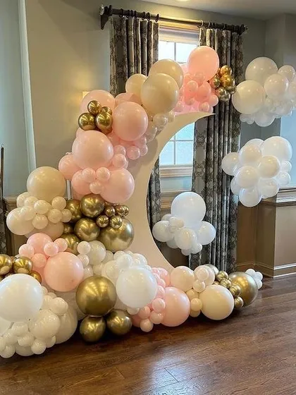 We are over the moon for this setup. A white crescent moon prop is surrounded by a cloud of pink, white, and gold balloons for a dreamy and ethereal photo backdrop.
