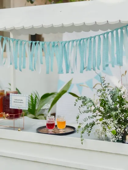 My charming refreshment cart, decorated with blue ribbons and flowers. It's set up with large glass dispensers of my signature mocktails, ready to serve thirsty guests.
