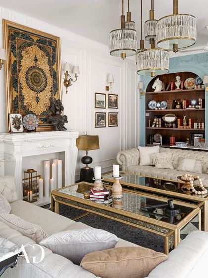 This view highlights the room's focal points: a grand fireplace topped with an intricate tapestry and a built-in bookshelf with a contrasting powder blue backing. These elements add layers of personality and curated charm to the space.