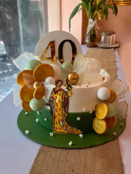 A special cake designed for a tarot card reader's 40th birthday. The design incorporates an illustration of a tarot card and is decorated with gold and green spheres that give it a mystical, magical feel.