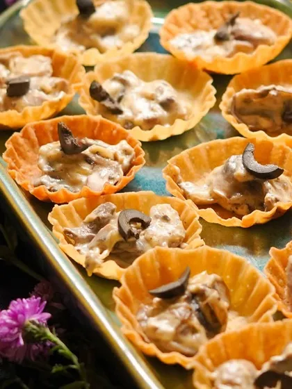 A closer look at the Creamy Mushroom Tarts, topped with black olives and served on a beautiful platter.