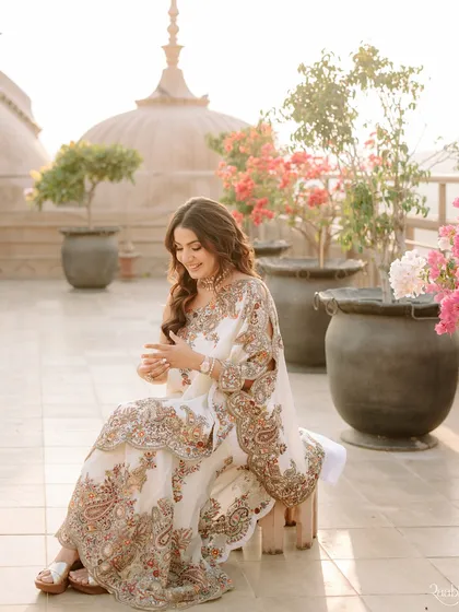A beautiful candid of the bride, Radheeka, against the backdrop of the domes at Fairmont Jaipur, surrounded by bougainvillea.