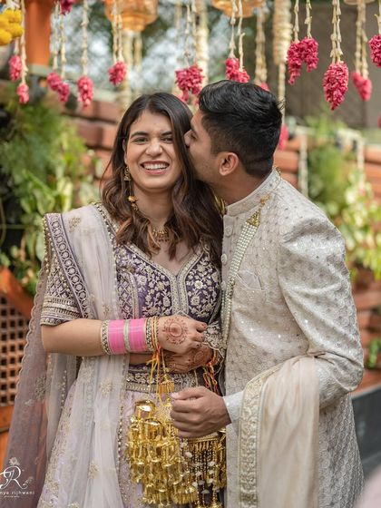A sweet kiss on the cheek during an intimate Delhi wedding. This photo captures a tender moment between the couple amidst the celebration, showcasing their affection and happiness.
