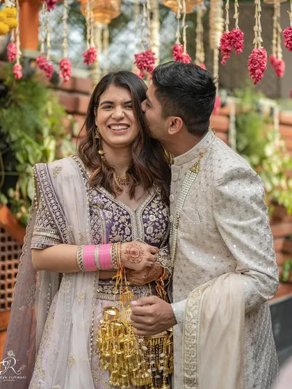 A sweet kiss on the cheek during an intimate Delhi wedding. This photo captures a tender moment between the couple amidst the celebration, showcasing their affection and happiness.