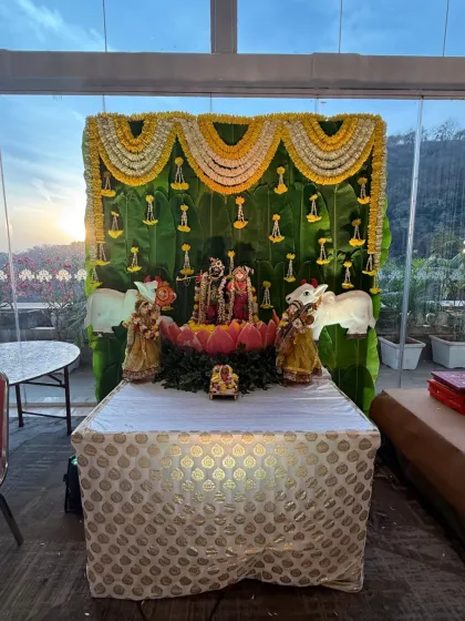 Even a simple ceremony can be made divine. Here, we created a beautiful outdoor altar with a backdrop of fresh banana leaves and garlands of white and yellow flowers, perfectly framing the deities against the evening sky.