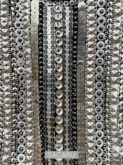 A detailed view of the meticulous hand embroidery on a brocade halter neck piece, showcasing rows of silver metal sequins and beads that create a stunning, light-catching texture.