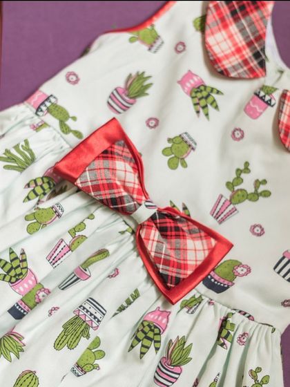 I love combining prints, like on this fun cactus-themed dress. The plaid collar and bow add a surprising and playful element to the design.