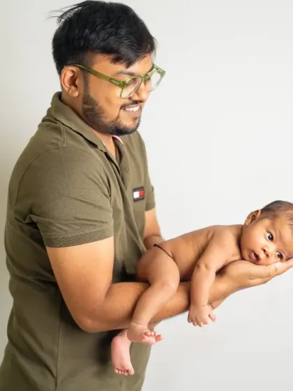 A proud father holds his newborn in his hands. This simple, classic portrait beautifully showcases just how small and precious a new baby is.