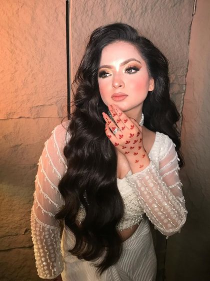 The 'Homa Doll' look is all about soft, romantic beauty. The makeup features a flawless base and gentle smokey eyes, paired with classic Hollywood waves.