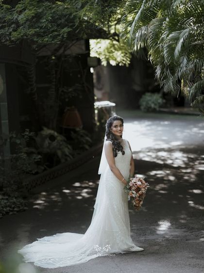 The bride stands in a beautifully lit garden path, her gown and veil creating a classic and elegant silhouette.