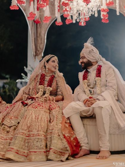 A candid, happy moment between Rahul and Aashi on their wedding day, seated together during the ceremony.