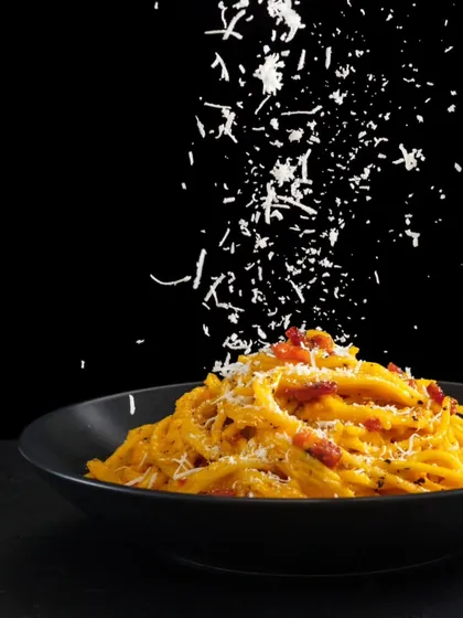A classic Italian pasta dish, elegantly plated and finished with a generous shower of parmesan cheese. We're here to elevate your special occasions with top-tier catering and authentic global flavors.