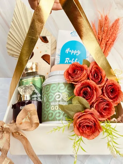 An elegant triangular hamper for Rakhi, decorated with beautiful red roses. This sophisticated gift includes perfume, tea, and chocolates, perfect for a brother or sister with refined taste.