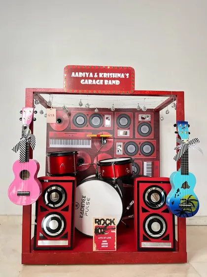 For the little rockstars in your life, I created this 'Garage Band' themed hamper. It's a complete stage setup in a box, featuring miniature guitars, a drum set, and a personalized marquee sign for an unforgettable birthday surprise.