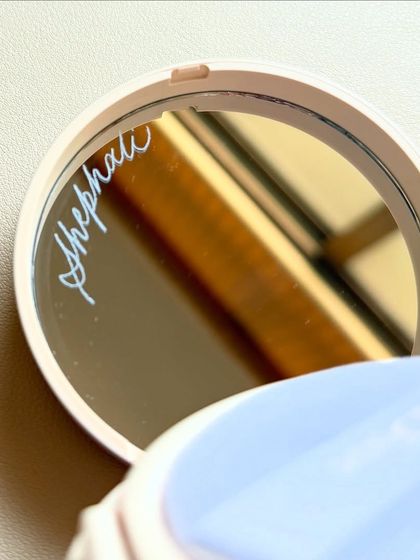 A closer look at the engraved Dior compact mirror, showing the clean lines and precision of the work.