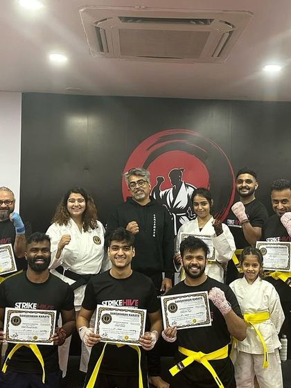 The entire group that passed their kickboxing belt test poses with their certificates, a moment of collective achievement.