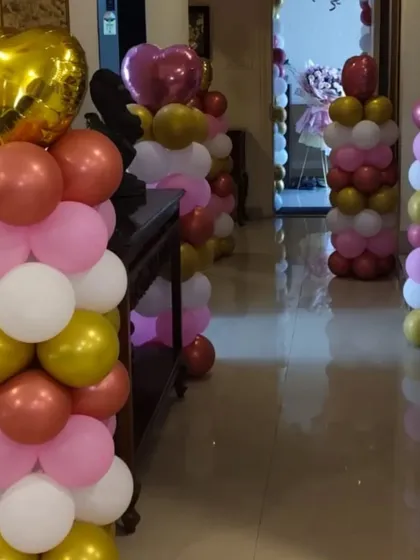 Simple balloon pillars can transform a hallway or entrance. These columns in pink, white, and gold add a touch of celebration and guide guests into the party.