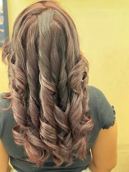 The back of a client's hair, showing off her new red hair color and the beautiful, cascading curls.