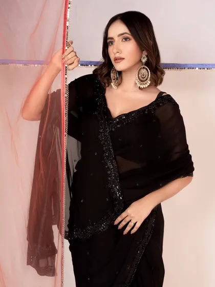 An elegant shot for a saree collection. The model's pose and the dramatic earrings give the simple black saree a sophisticated, party-ready look.