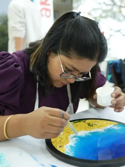 A participant adds the final touches to her resin beach art, creating realistic wave patterns.
