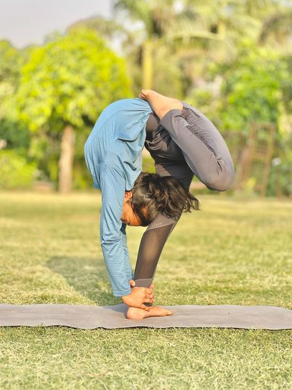 A student holding a deep standing forward bend with a twist. This was taken during one of our morning sessions in the park.