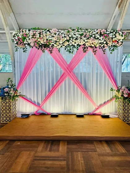 This simple and elegant setup was designed for a Mayra ceremony. We used pink drapes and a floral header to create a beautiful backdrop for the ritual.