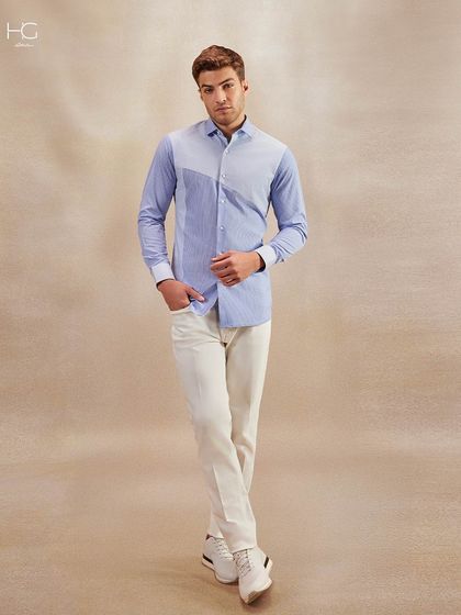 A full-length view of the striped panel shirt, paired with off-white trousers and sneakers. This shows how a formal shirt can be styled for a smart, contemporary look.