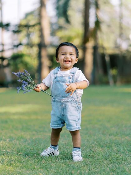 A happy little boy in overalls, holding a bunch of lavender. A sweet, candid shot from an outdoor session.