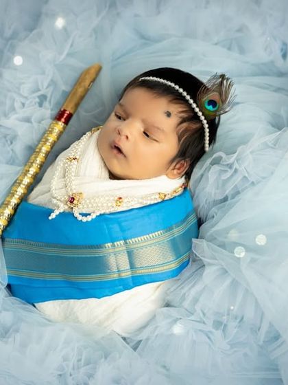 A dreamy version of the newborn Krishna shoot, with the baby surrounded by soft blue tulle and sparkling lights for a magical effect.