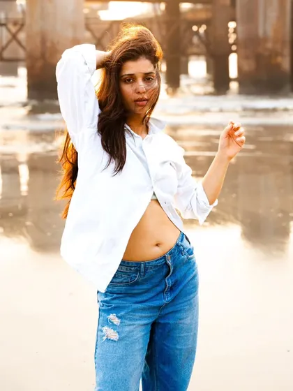 The classic white shirt and jeans look, elevated by the golden sunset light. The backlighting creates a beautiful rim light on her hair.