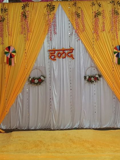 A clean shot of a Haldi backdrop with yellow and white drapes, ready for the ceremony. The hanging decorations add a nice touch.