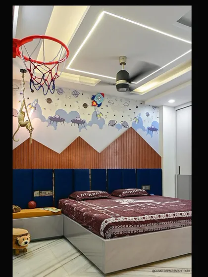 Designing for kids is always fun and requires creativity. This space-themed bedroom is designed to spark imagination, featuring a custom wallpaper mural, mountain-shaped wood paneling, and playful elements like a basketball hoop and a monkey rope light.