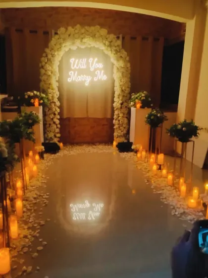 A truly magical proposal setup. I used a candlelit pathway leading to a floral arch with a "Will You Marry Me?" neon sign to create an unforgettable moment.