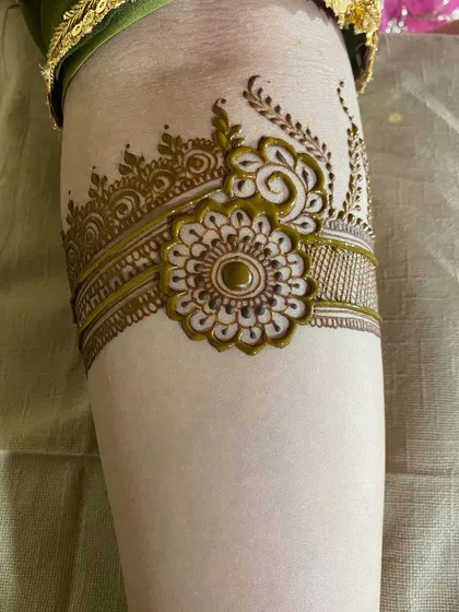 A simple and elegant henna arm band featuring a central flower.