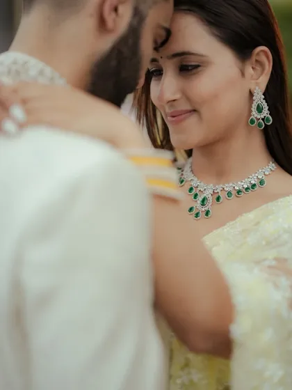 An intimate close-up capturing a quiet moment of connection. The focus on the couple's expressions and the elegant details of their attire, like the emerald jewelry, makes this a powerful cinematic portrait from a Mumbai engagement shoot.
