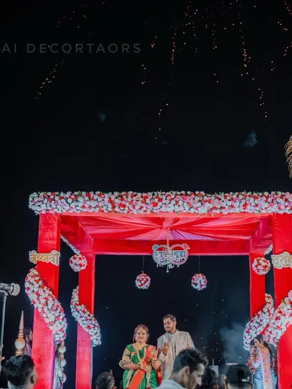 A magical moment under the wedding mandap as fireworks light up the night sky. This image captures the couple during their ceremony in our beautifully decorated red floral mandap.