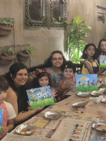 A table full of young artists and their parents enjoying the canvas painting session during the birthday festivities.
