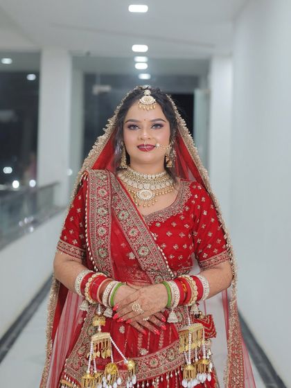 A happy bride posing for the camera in her red lehenga. Her makeup is fresh and bright, with a smile that shows her confidence.