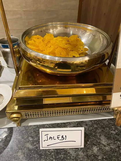 Freshly made Jalebis, glistening with sugar syrup, ready to be served at a Mata ki Chowki function. Their bright color and sweet taste bring joy to any event.