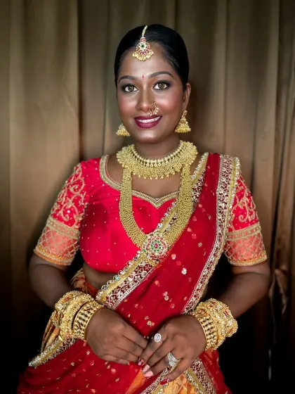 A full portrait of the bride, looking confident and beautiful in her traditional red and gold attire.